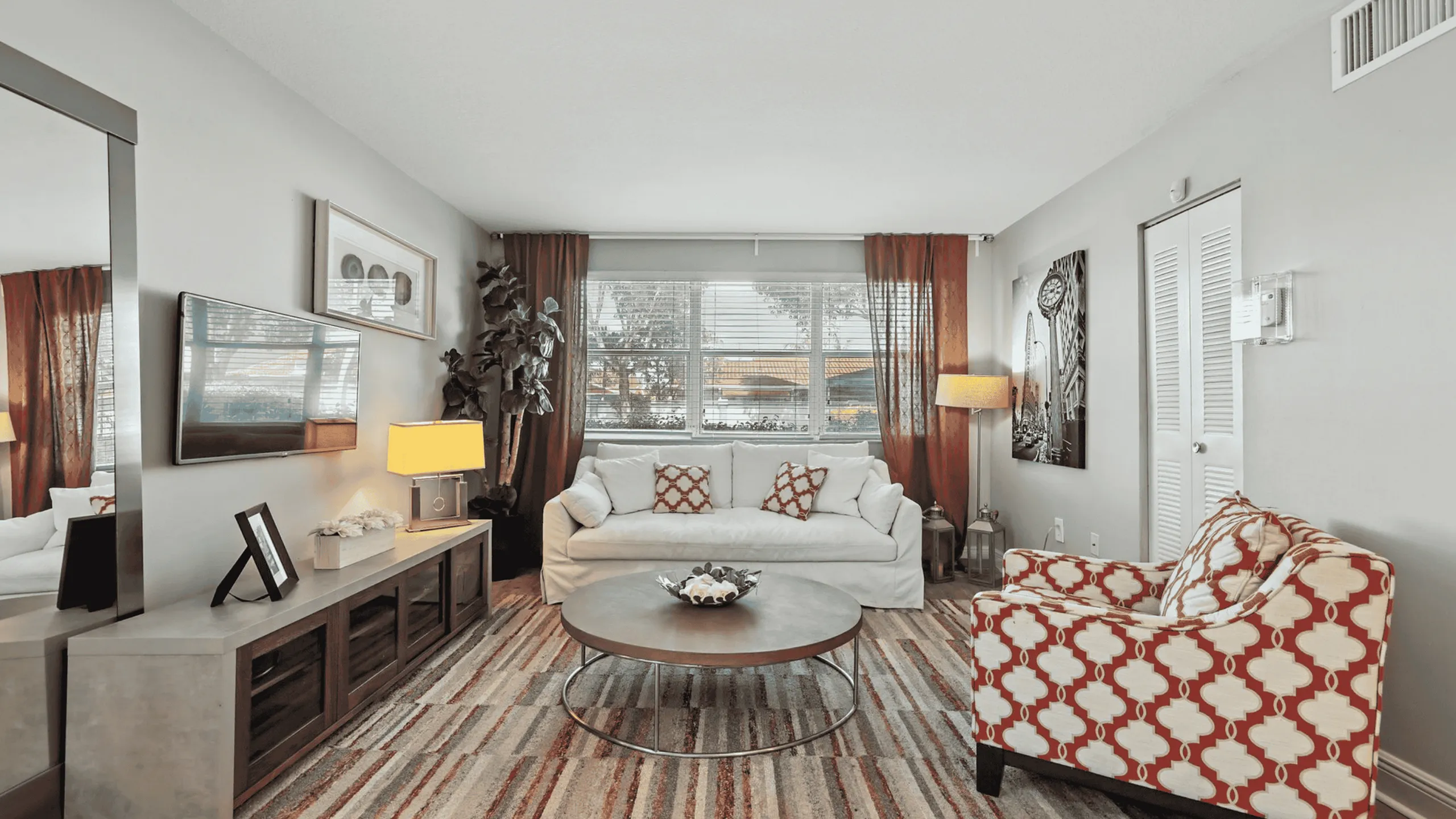 Inviting living room with chic decor, featuring a comfortable white sofa, stylish patterned armchair, and elegant modern accents.