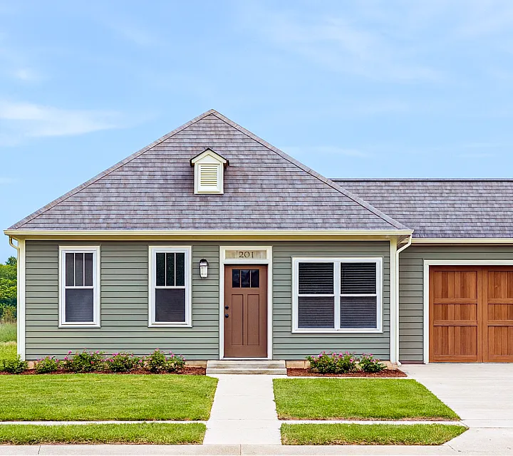 Charming single-story home with a modern green facade, inviting front door, and well-maintained landscaping in a serene setting.