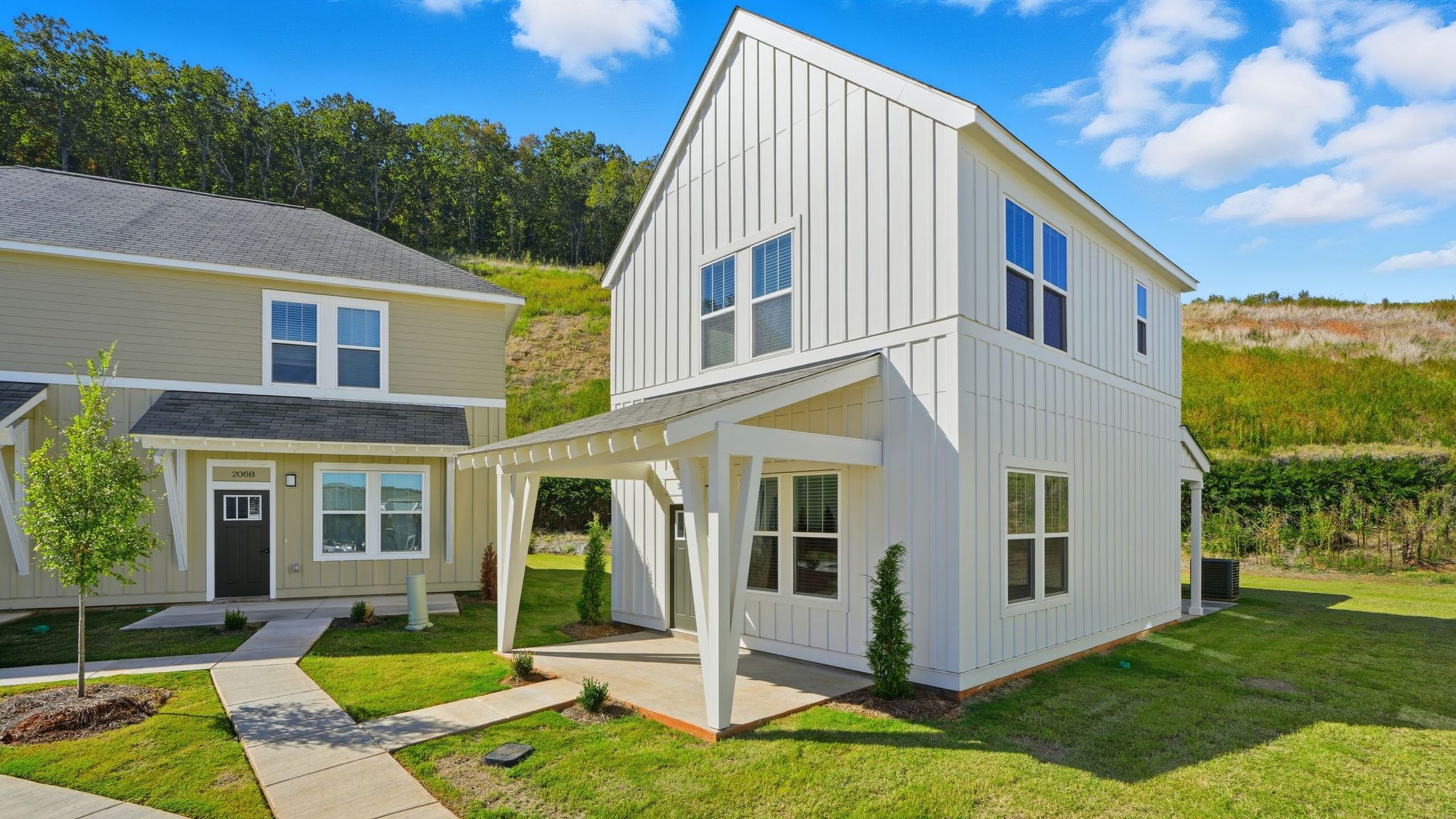 Charming modern townhouse with a sleek white exterior, surrounded by lush green lawns, offering a serene suburban lifestyle.