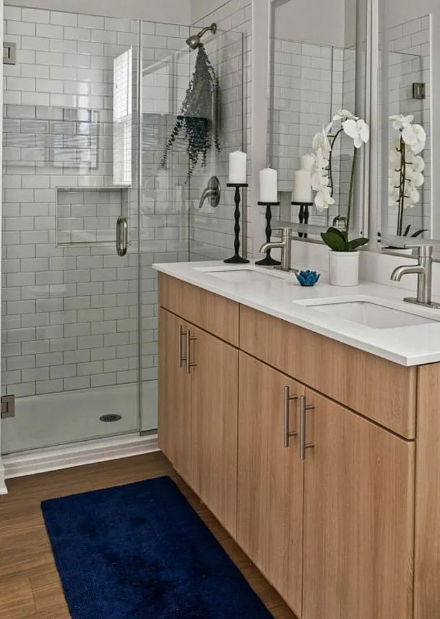 Modern bathroom featuring a sleek glass-enclosed shower, elegant dual-sink vanity, and stylish decor with orchid accents.