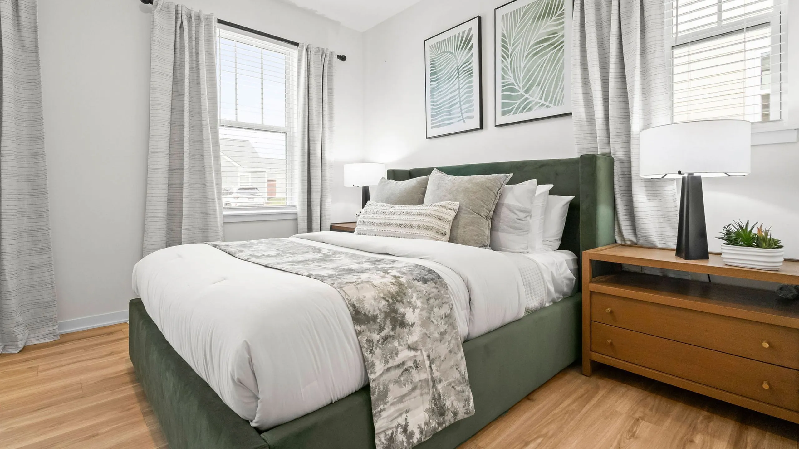 Charming bedroom with plush bedding, wooden nightstand, and modern decor, offering a cozy retreat for relaxation.