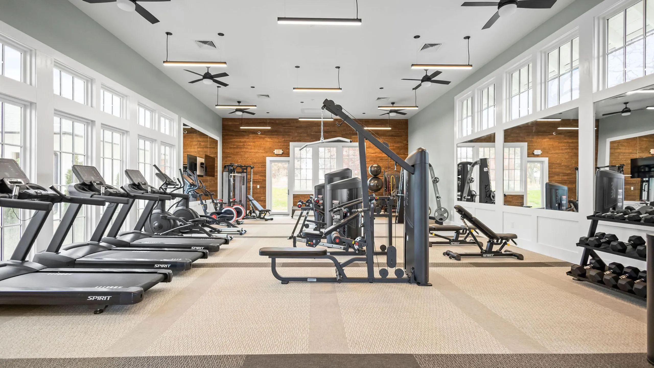Modern fitness center with state-of-the-art equipment, including treadmills, weight machines, and ample natural light for an energizing workout experience.