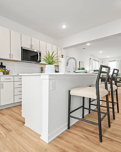 Modern kitchen with sleek white cabinets, a spacious island, and stylish barstools creating an inviting open-concept living space.