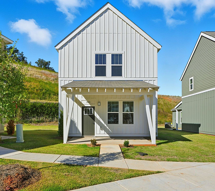 Charming, modern two-story house with a cozy front porch nestled in a serene suburban neighborhood surrounded by lush greenery.