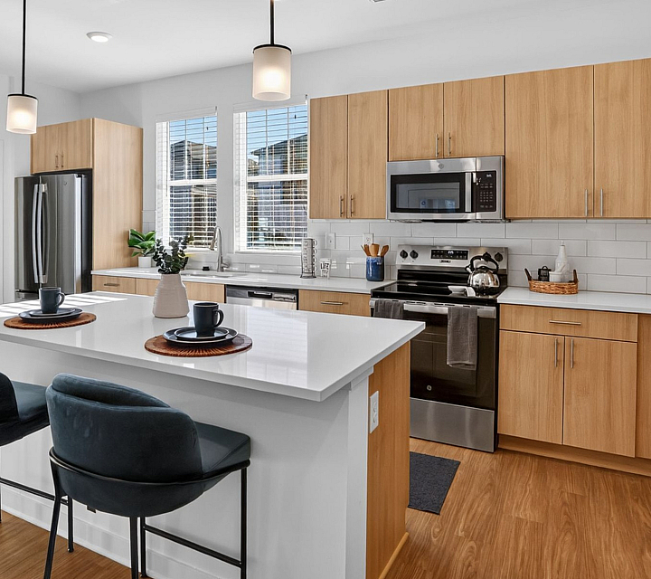Modern kitchen with sleek wooden cabinets, stainless steel appliances, and a stylish breakfast bar with elegant barstools.