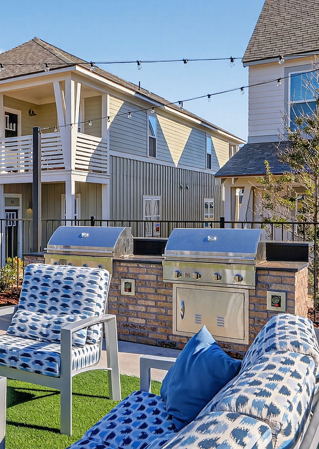 Charming outdoor patio with modern seating, BBQ grill, and lush greenery, perfect for relaxing and entertaining.