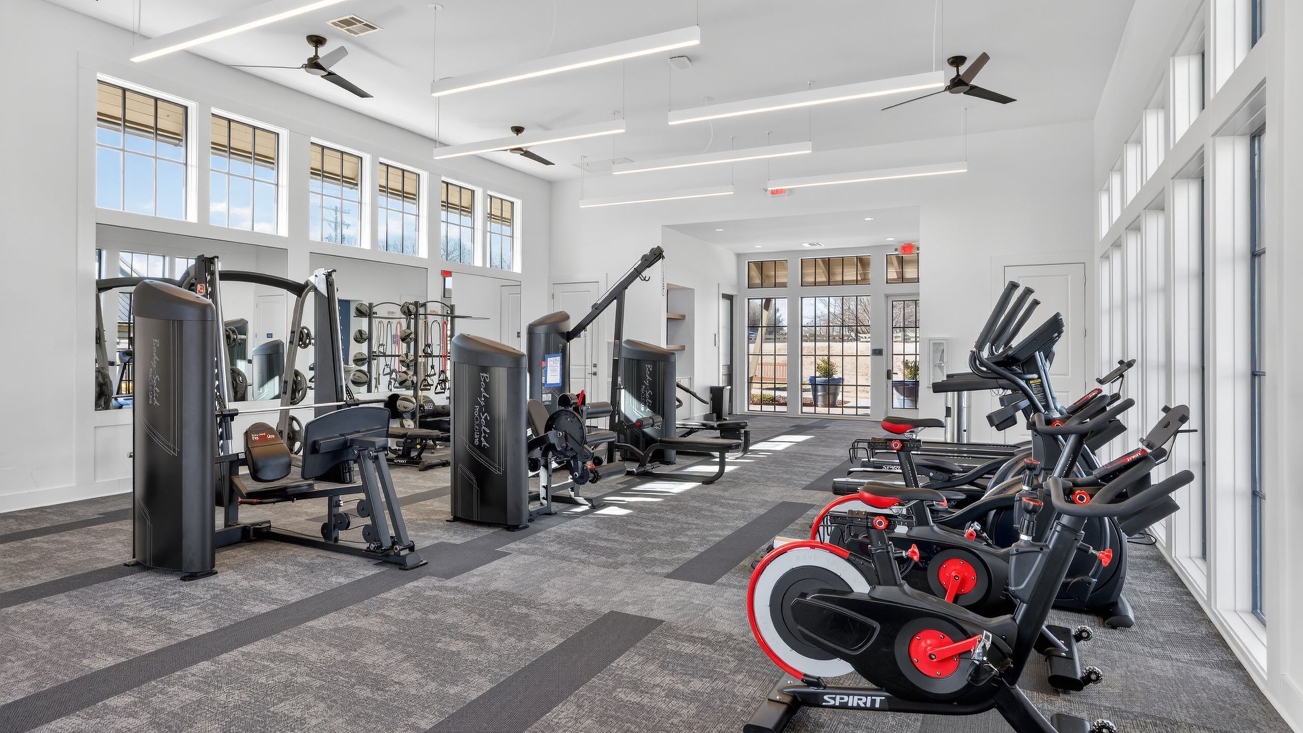 Modern fitness center with state-of-the-art exercise equipment and large windows letting in natural light.
