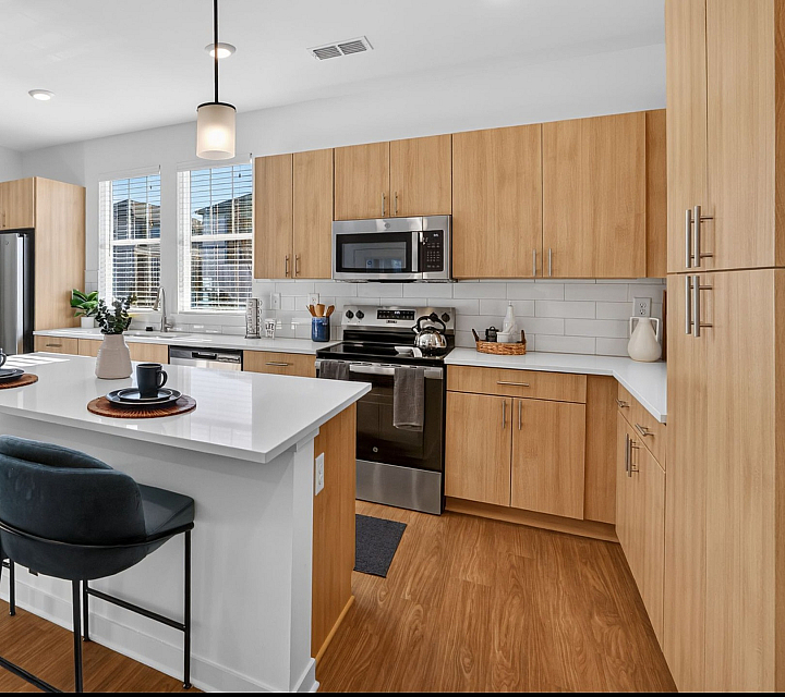 Chic and modern kitchen with light wood cabinetry, stainless steel appliances, and inviting breakfast bar seating.