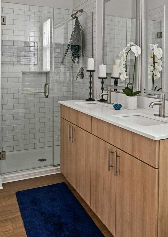 Elegant modern bathroom with a glass-enclosed shower, sleek wood cabinetry, and stylish decor.