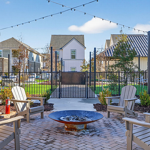 Charming outdoor patio with cozy fire pit surrounded by Adirondack chairs, set in a vibrant community garden, perfect for relaxation and socializing.