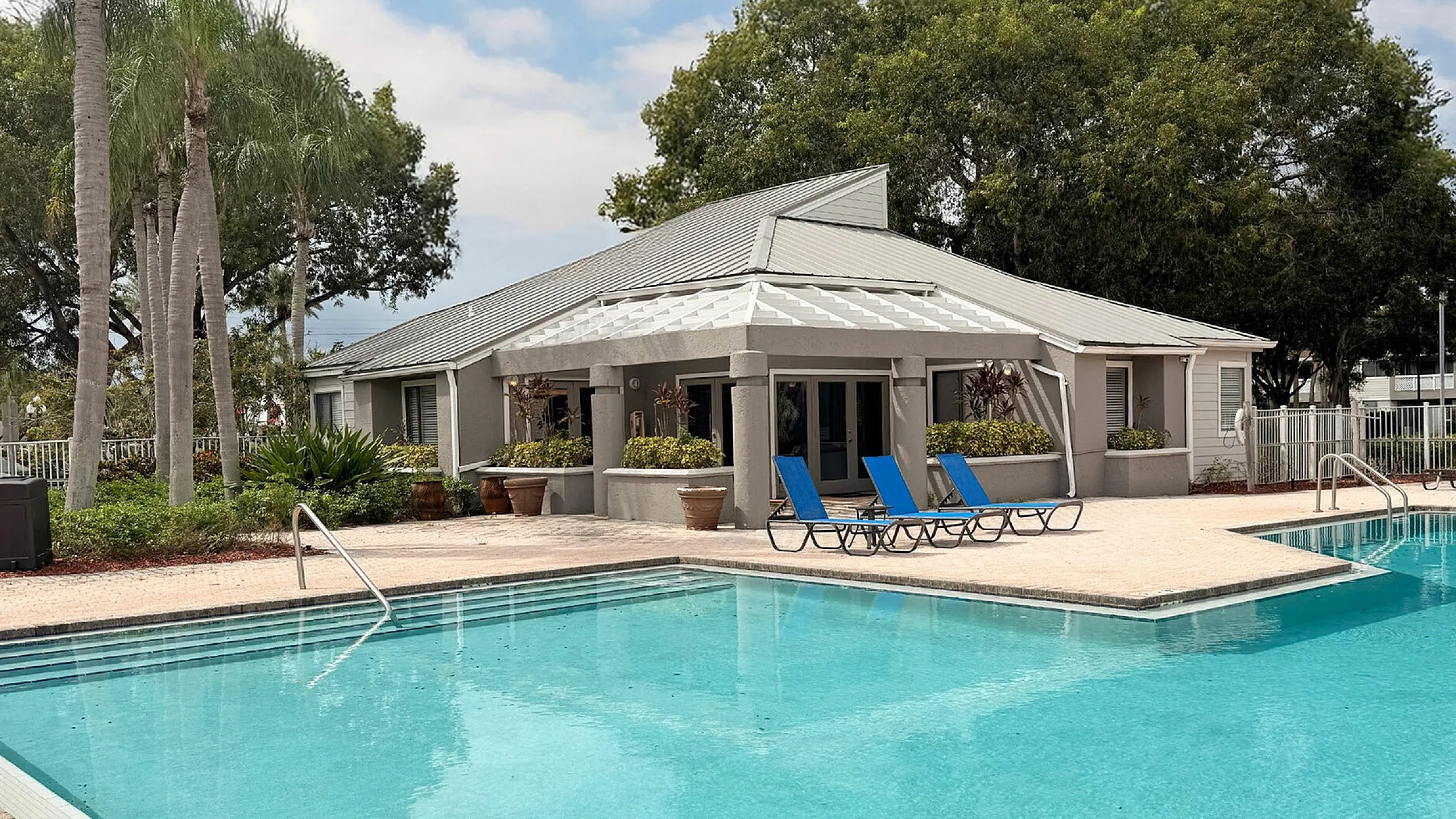 Inviting residential pool with vibrant blue lounge chairs and lush green surroundings, ideal for relaxation and leisure.