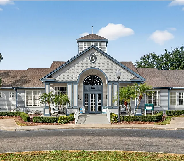 Inviting apartment complex entrance with elegant architectural design, surrounded by lush palm trees and well-manicured landscaping.