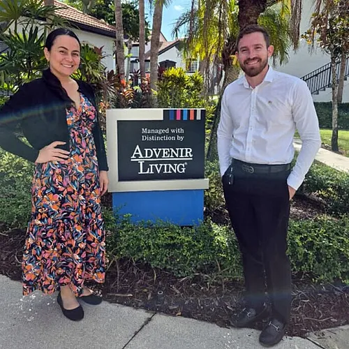 Welcoming atmosphere at Advenir Living, featuring smiling staff in a lush, green setting with modern signage.