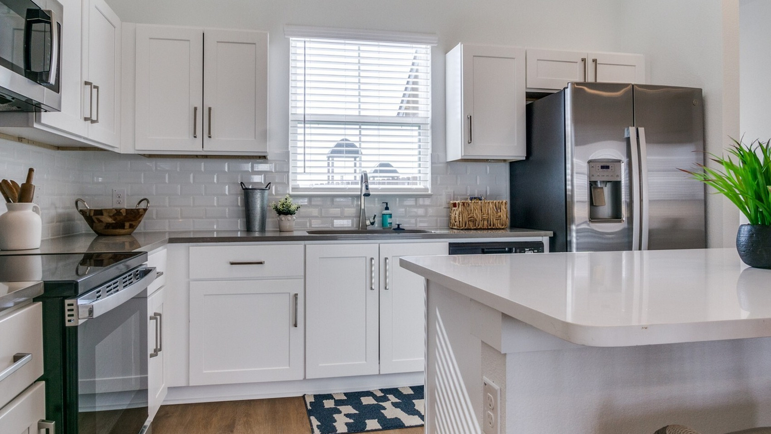 Modern kitchen with sleek stainless steel appliances, glossy white cabinetry, and a chic breakfast bar adorned with vibrant greenery.