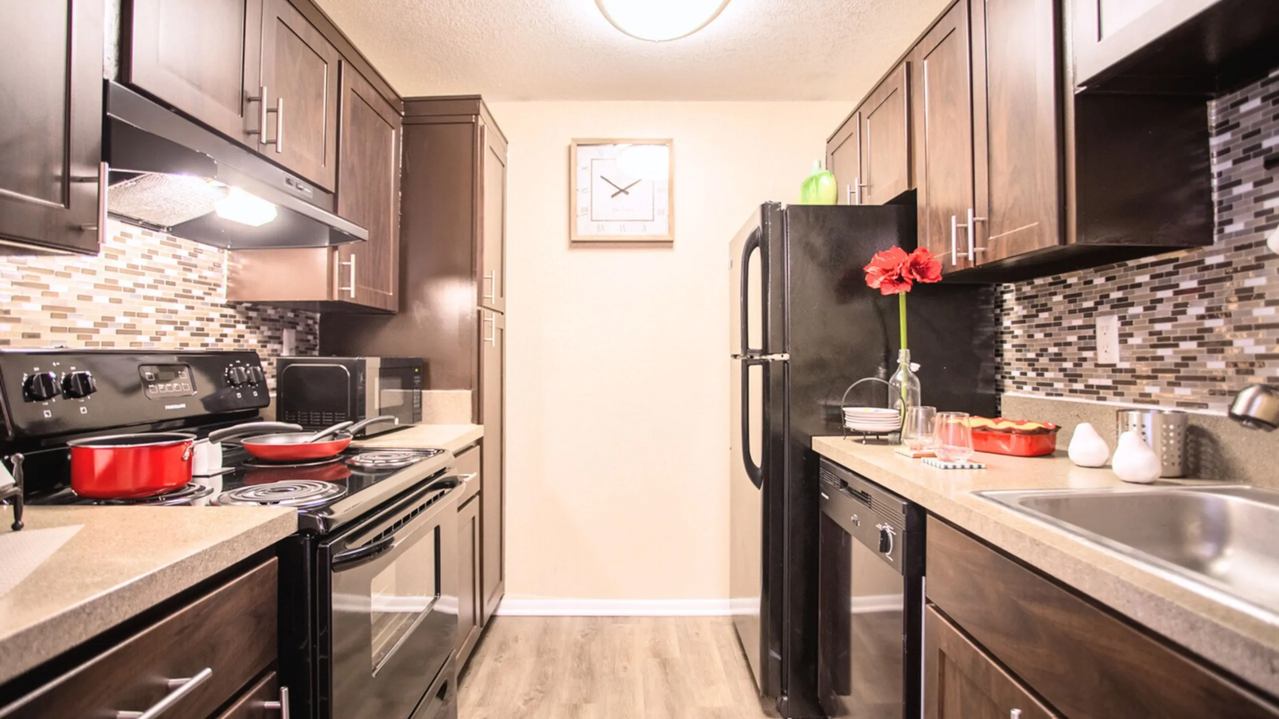 Chic modern kitchen with dark wood cabinets, stylish backsplash, and stainless steel appliances, exuding a welcoming atmosphere.