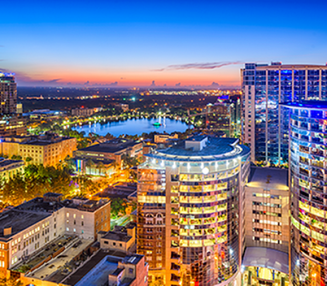 Vibrant cityscape view showcasing modern high-rise buildings and a serene lakeside panorama at dusk.