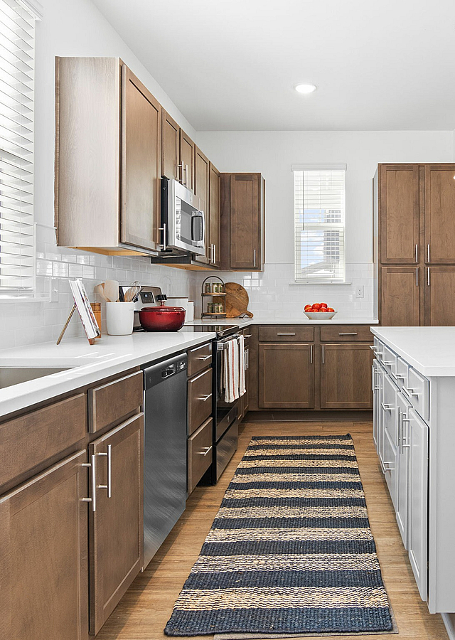 Modern kitchen with sleek wooden cabinets, spacious white countertops, and chic pendant lighting enhancing the open-concept design.