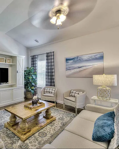 Inviting living room with elegant decor, featuring cozy seating, a stylish entertainment center, and a serene beach artwork.