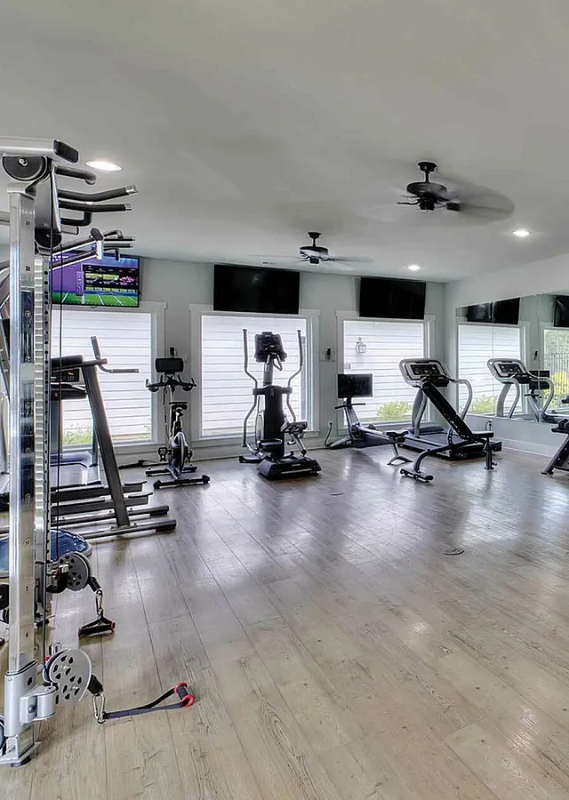Modern fitness center with state-of-the-art equipment, sleek wood flooring, and vibrant natural lighting.