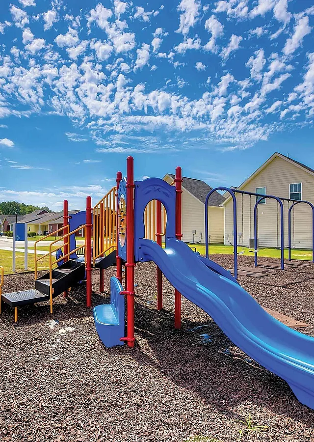 Inviting community playground with vibrant slides and swings under a clear blue sky, perfect for family fun and outdoor recreation.