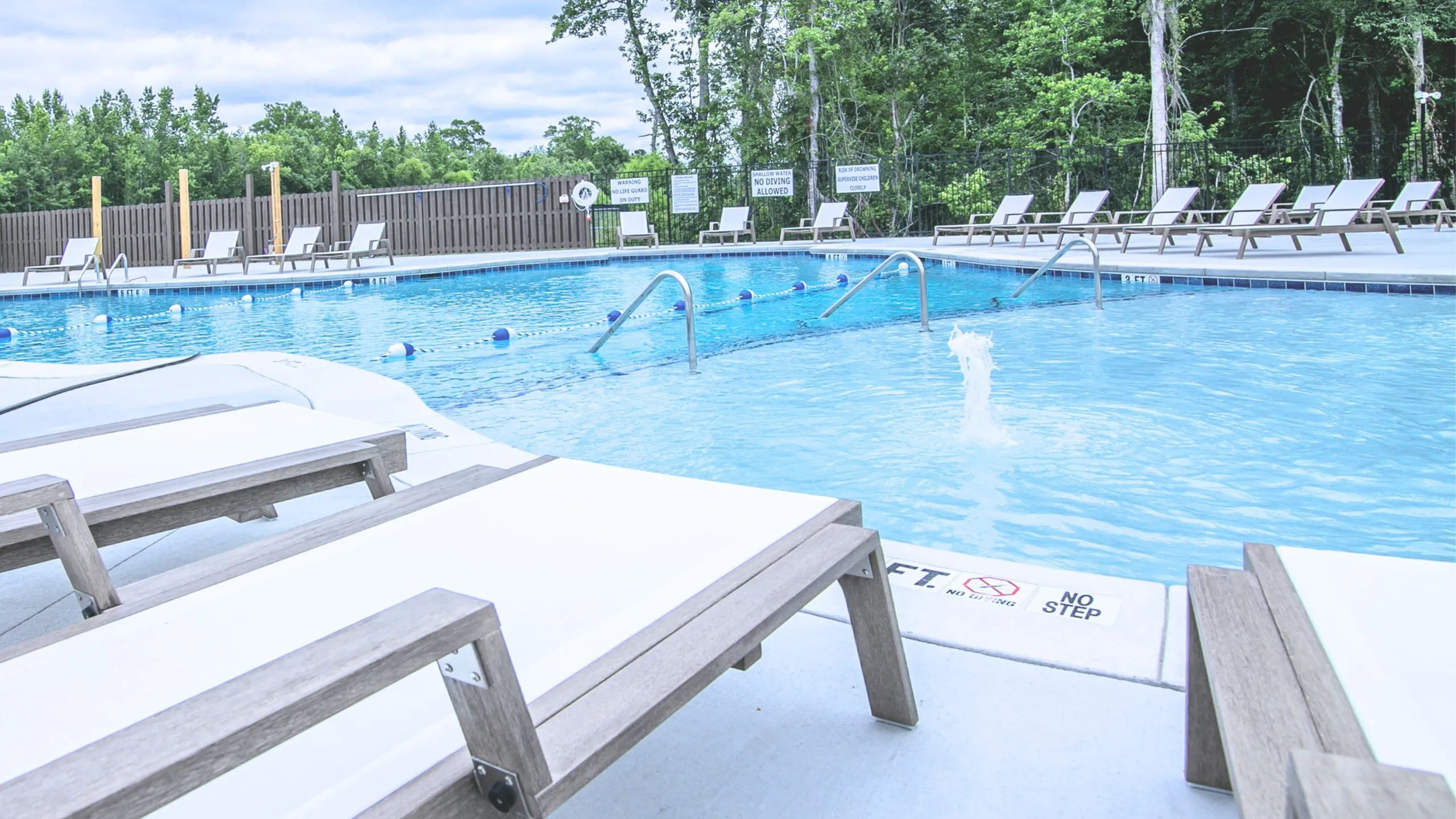 Inviting outdoor swimming pool area with sleek loungers and serene lush greenery, perfect for relaxation and leisure.