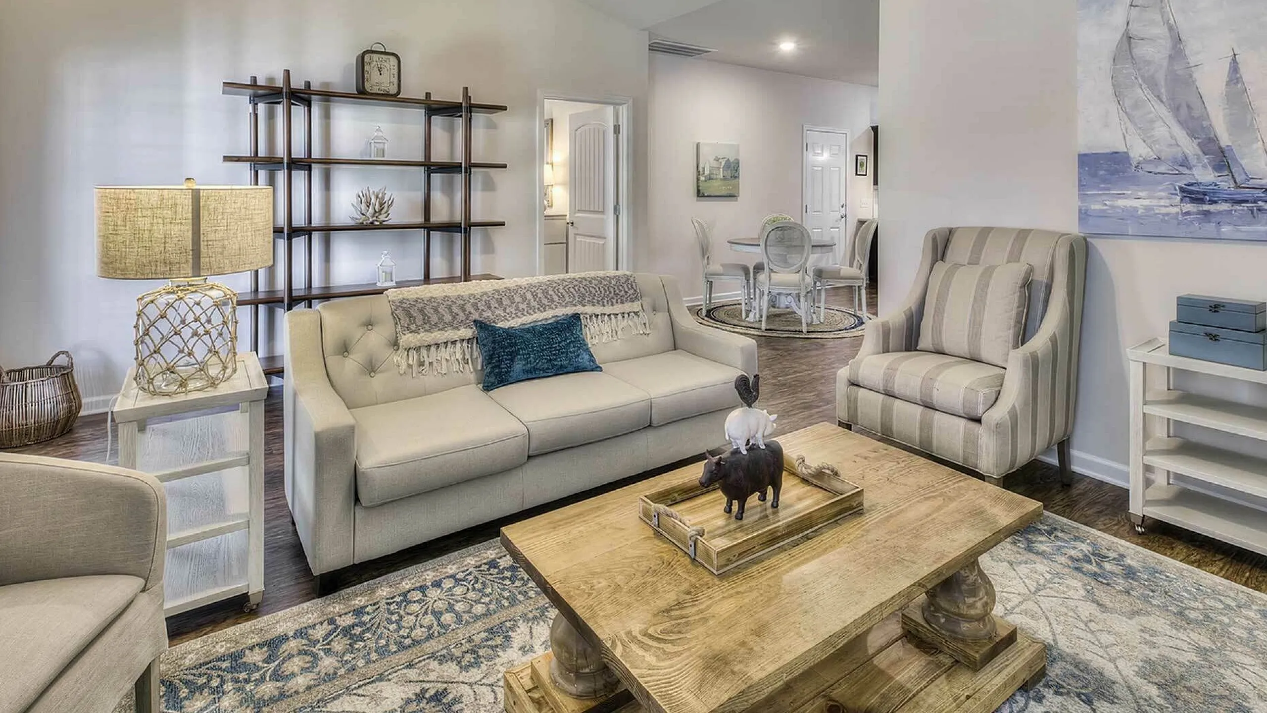 Charming living room with elegant decor, featuring a cozy sofa, stylish armchair, and nautical-themed artwork, perfect for relaxing and entertaining.