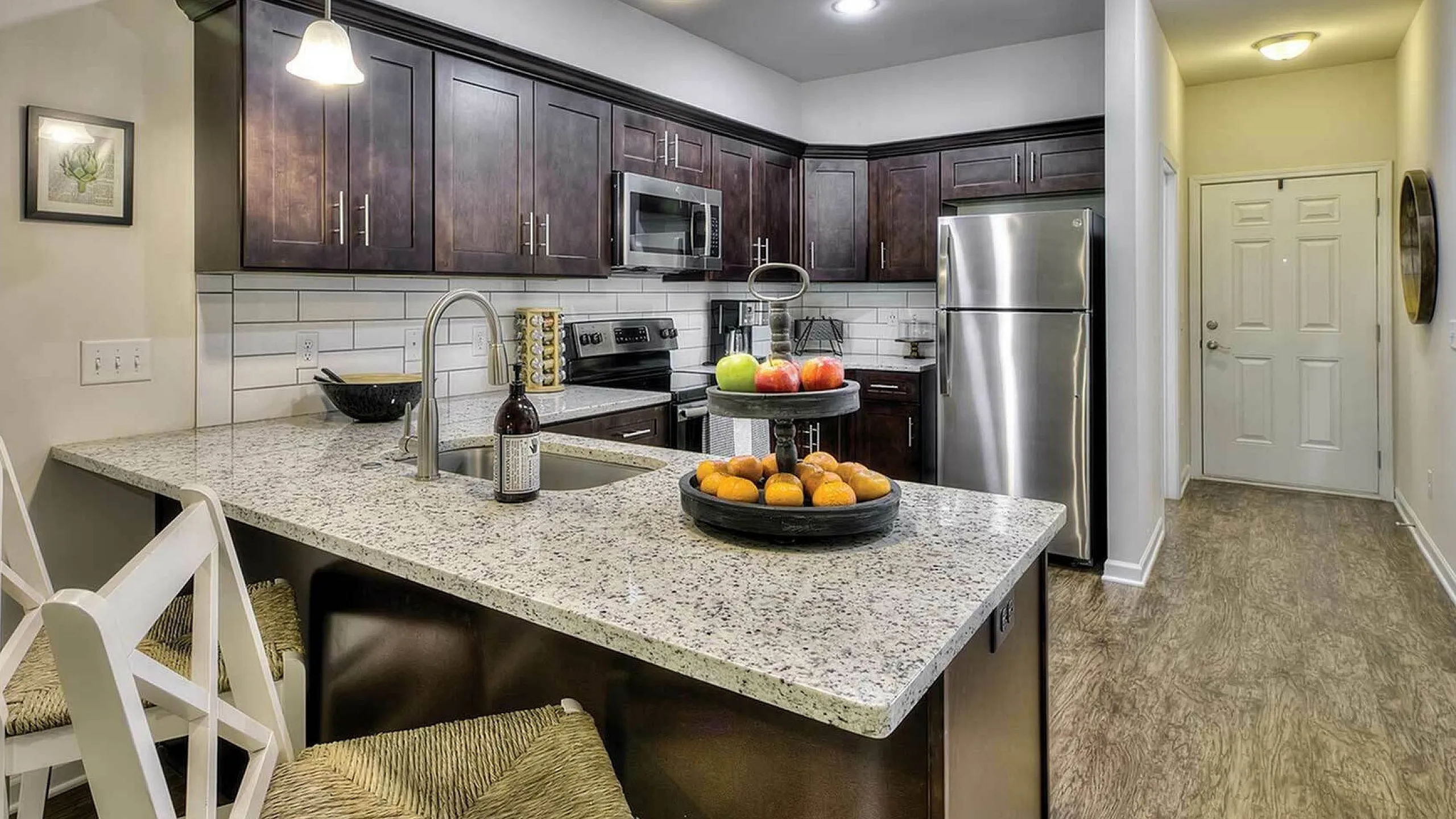 Modern kitchen with sleek granite countertops, stainless steel appliances, and chic pendant lighting. Cozy breakfast bar with stylish seating, creating an inviting space for dining and entertaining.