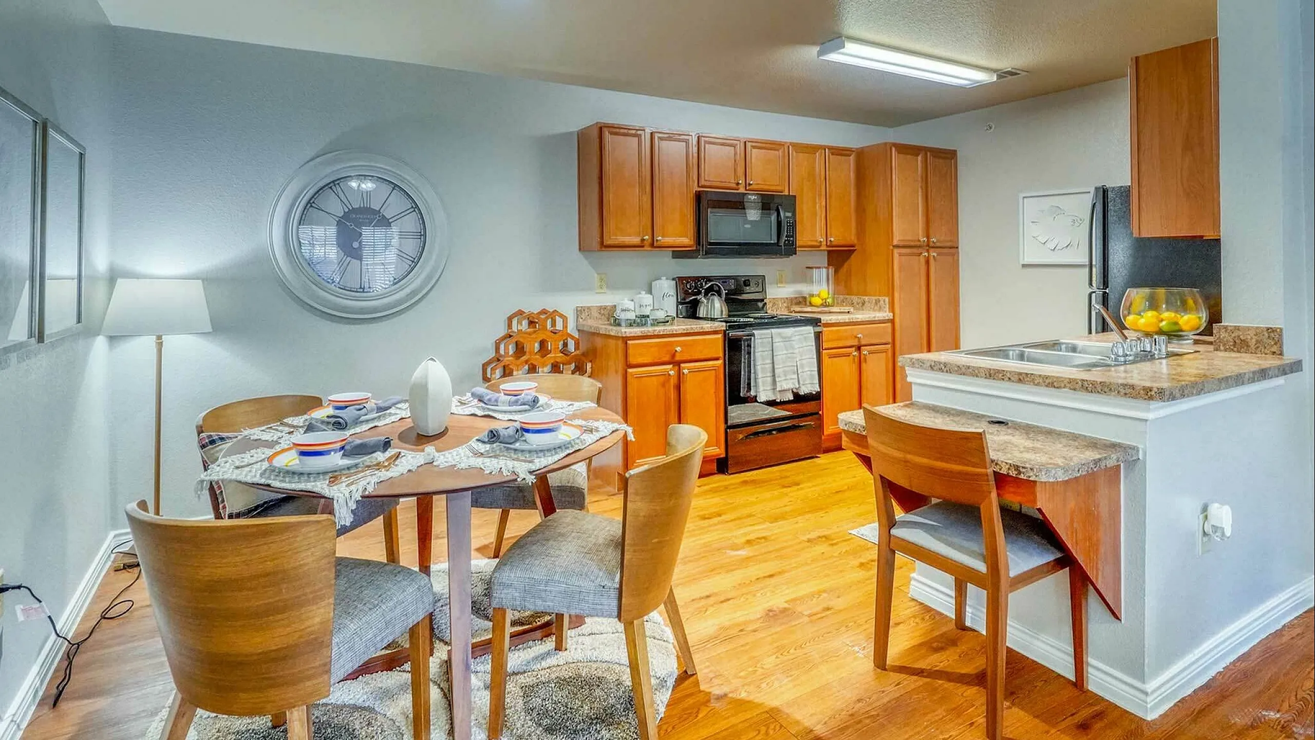 Contemporary dining area with elegant hardwood floors adjacent to a modern kitchen featuring rich wooden cabinetry and sleek countertops.