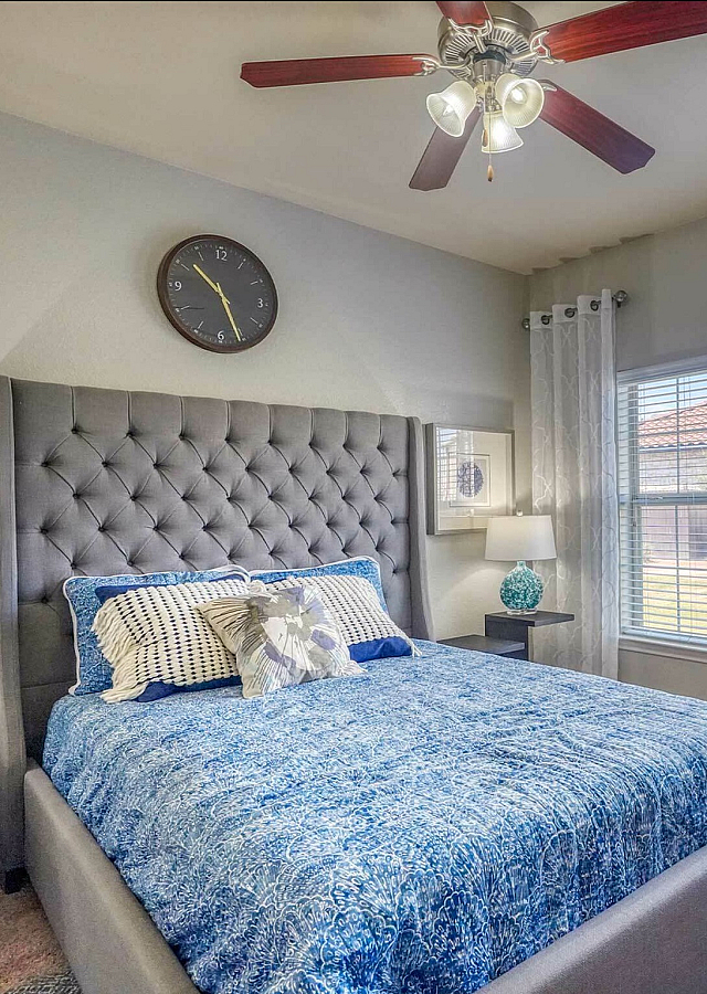Bright and inviting bedroom with elegant tufted headboard, chic decor, and large sunny windows.