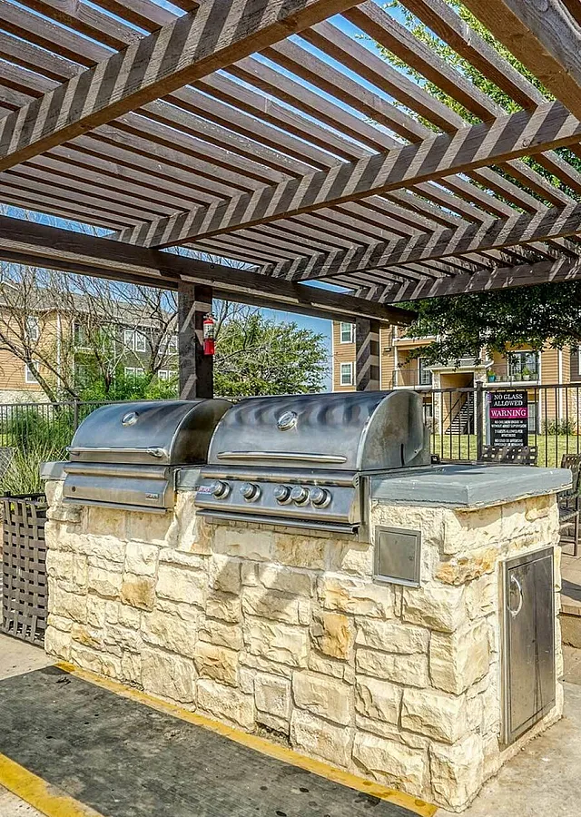 Inviting outdoor barbecue area with stylish pergola, perfect for entertaining in a vibrant apartment community.