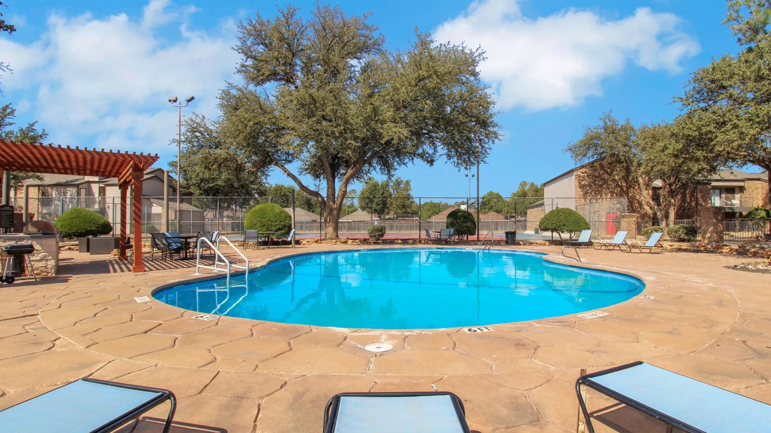 Charming outdoor pool area with inviting lounge chairs, surrounded by lush trees and a serene atmosphere.
