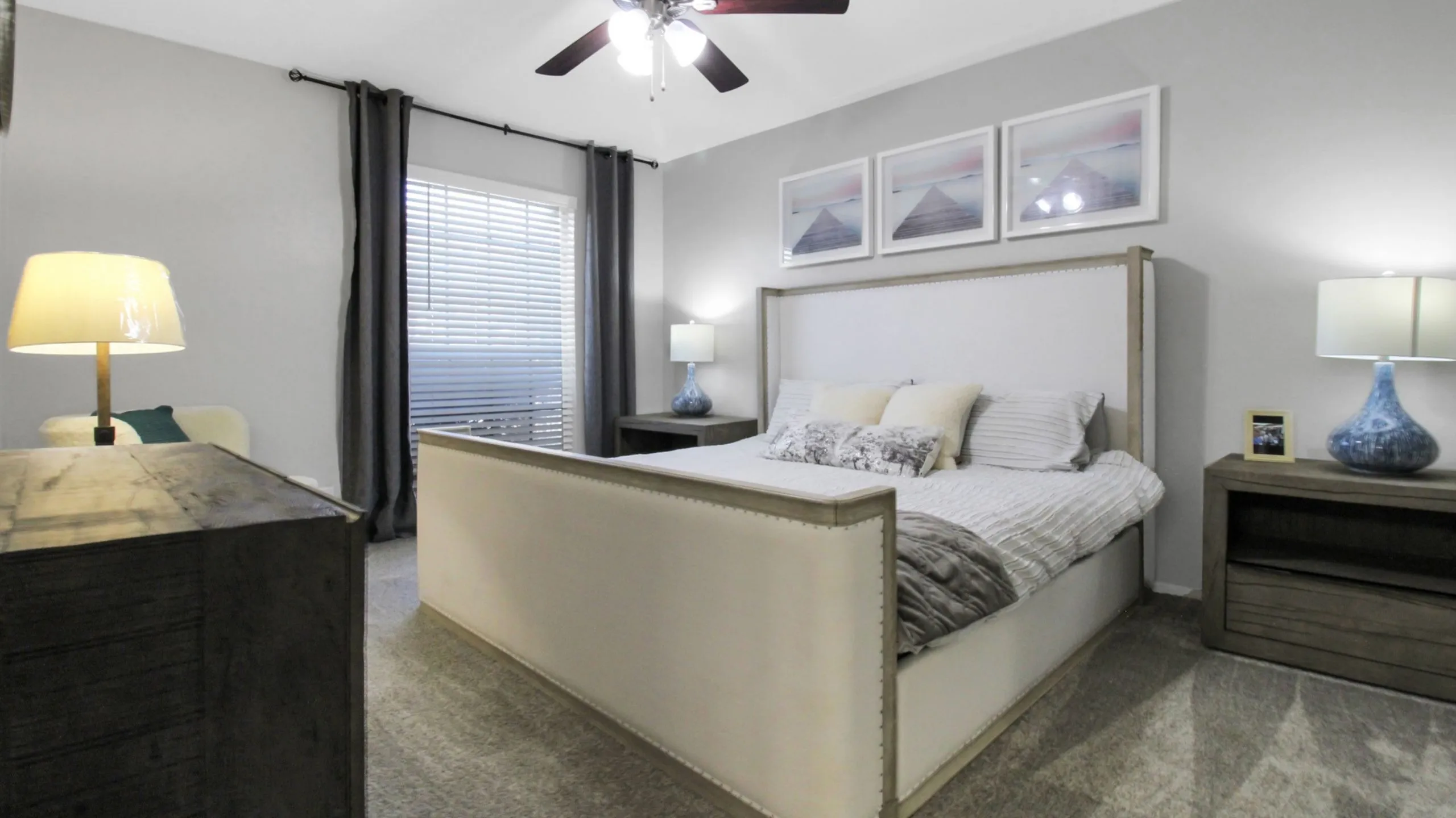 Inviting bedroom with a plush bed, elegant wooden furniture, stylish lamps, and modern decor.