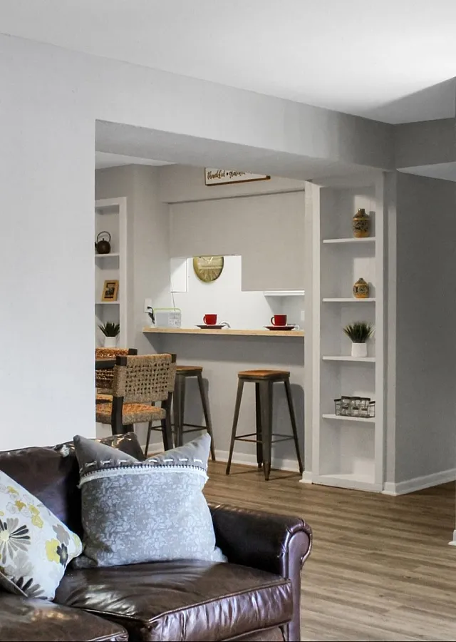 Inviting living area with modern decor, featuring a comfortable leather sofa, stylish floor lamp, and a cozy breakfast bar with stools.