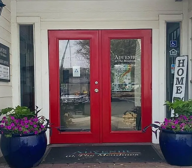 Inviting entrance with bright red doors and vibrant potted flowers, showcasing a welcoming atmosphere.