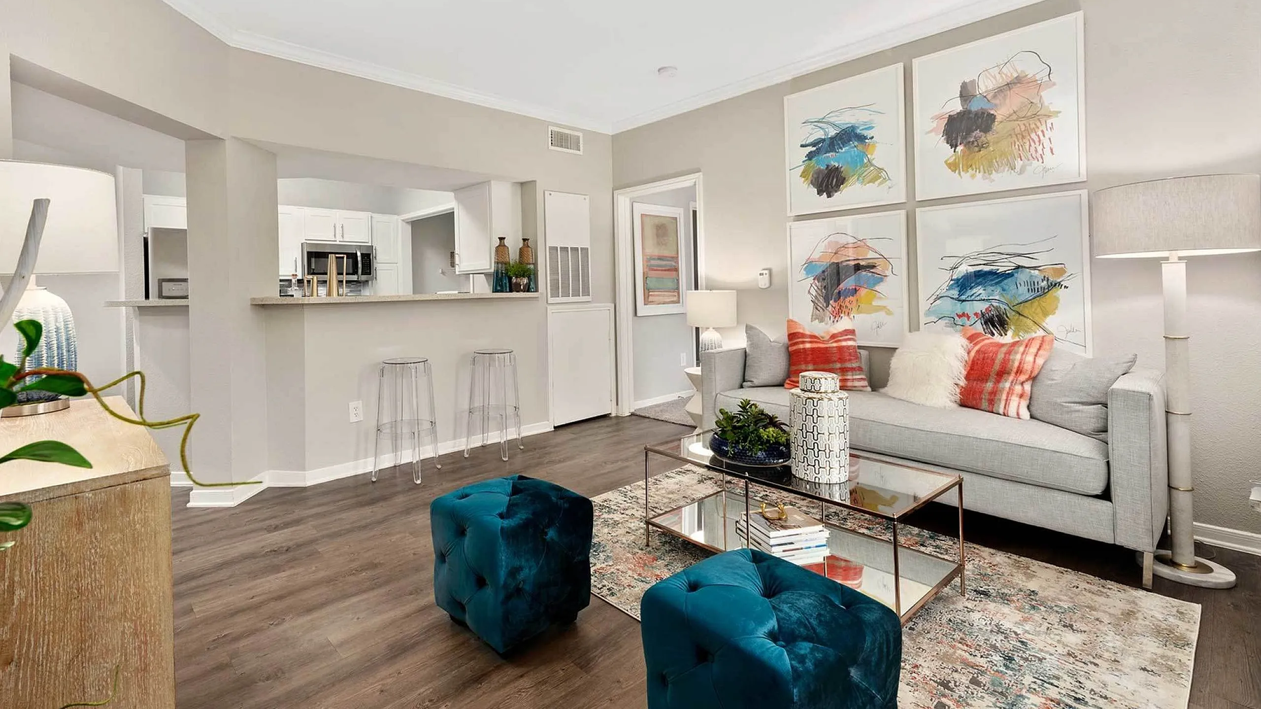 Inviting living room with modern decor, vibrant artwork, and an open kitchen view. Elegant design with plush seating and a cozy ambiance.