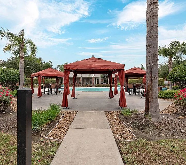 Luxurious outdoor setting with elegant red cabanas, picturesque landscaping, and a sparkling pool, perfect for relaxation and entertaining.