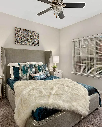 Bright and inviting bedroom featuring a plush upholstered bed with stylish bedding, modern bedside tables with lamps, and a large window bringing in natural light.