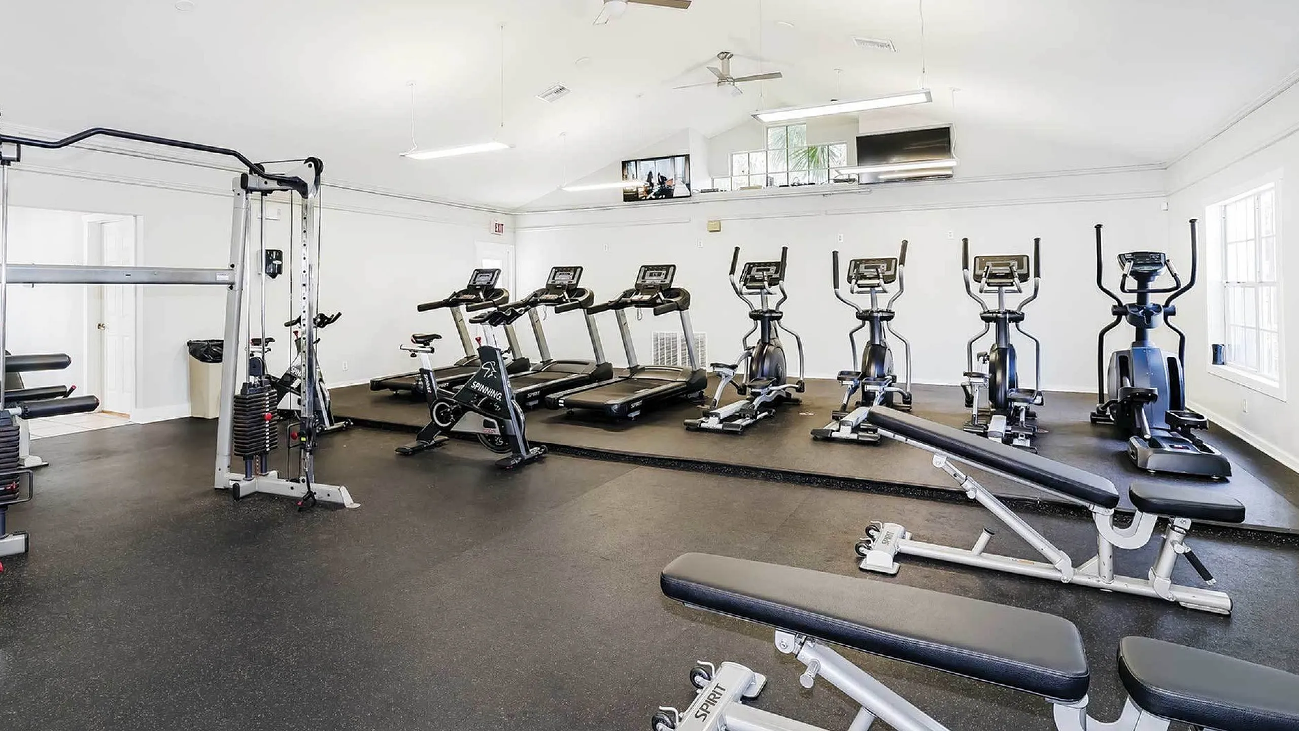 Spacious modern gym equipped with treadmills, elliptical machines, and versatile weight stations for a complete workout experience.