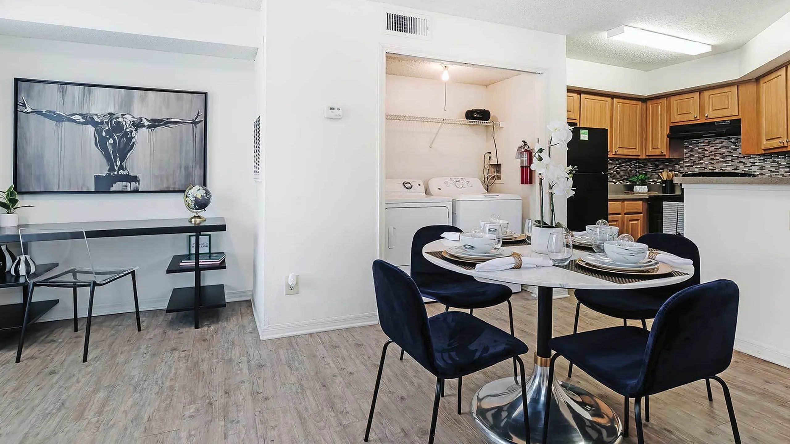 Bright and inviting open-concept dining area with modern decor, stylish kitchen, and in-unit laundry space, perfect for comfortable living.