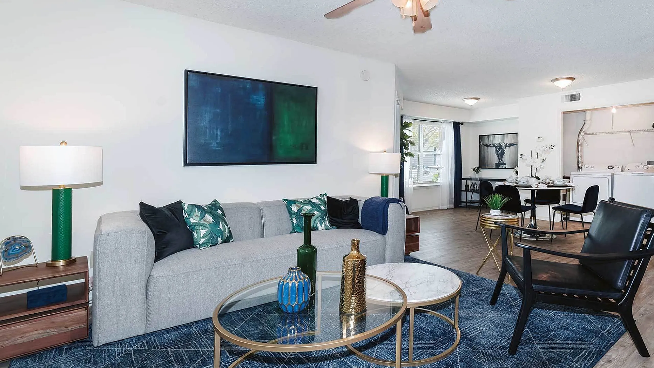 Bright, modern living room with stylish furniture and open dining area, accented by contemporary lighting and art.