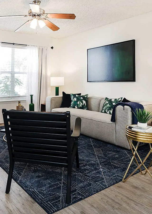Chic living room featuring a modern sofa, vibrant decor, and sleek wooden flooring under a stylish ceiling fan.