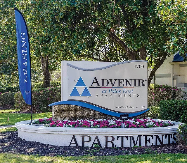 Welcome to Advenir at Polos East Apartments, a serene community sign surrounded by lush greenery and vibrant flowers.