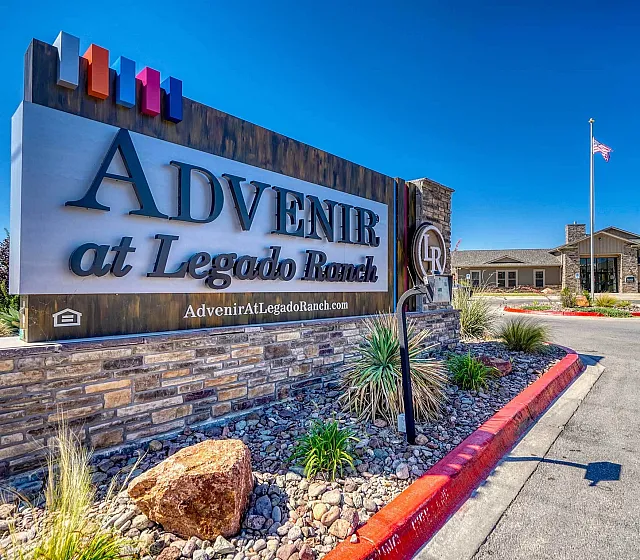 Welcome to Advenir at Legado Ranch, beautifully landscaped entrance with modern signage and a well-maintained driveway under a clear blue sky.