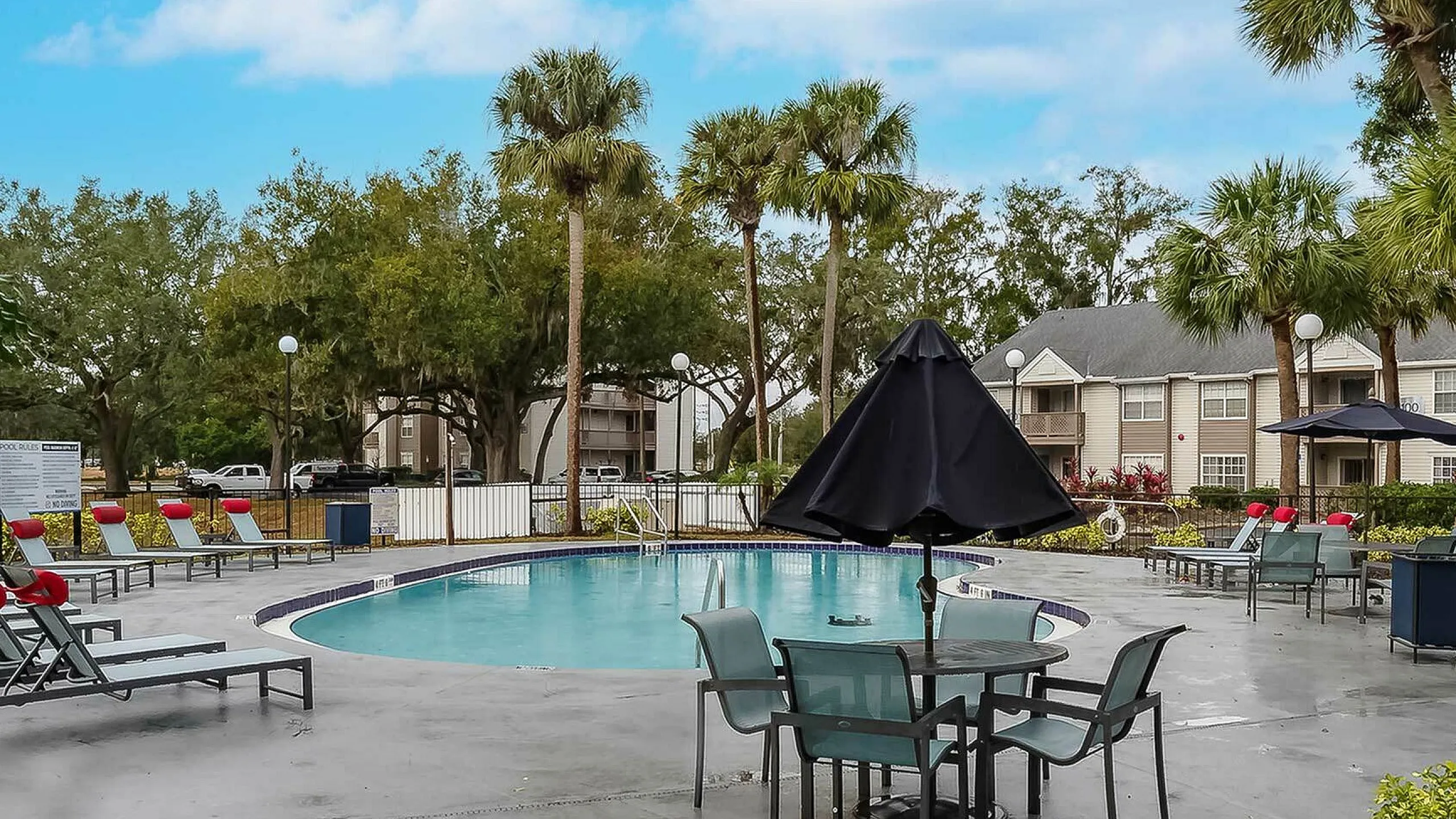 Charming outdoor pool area with lush greenery and stylish loungers under a clear blue sky, perfect for relaxation.