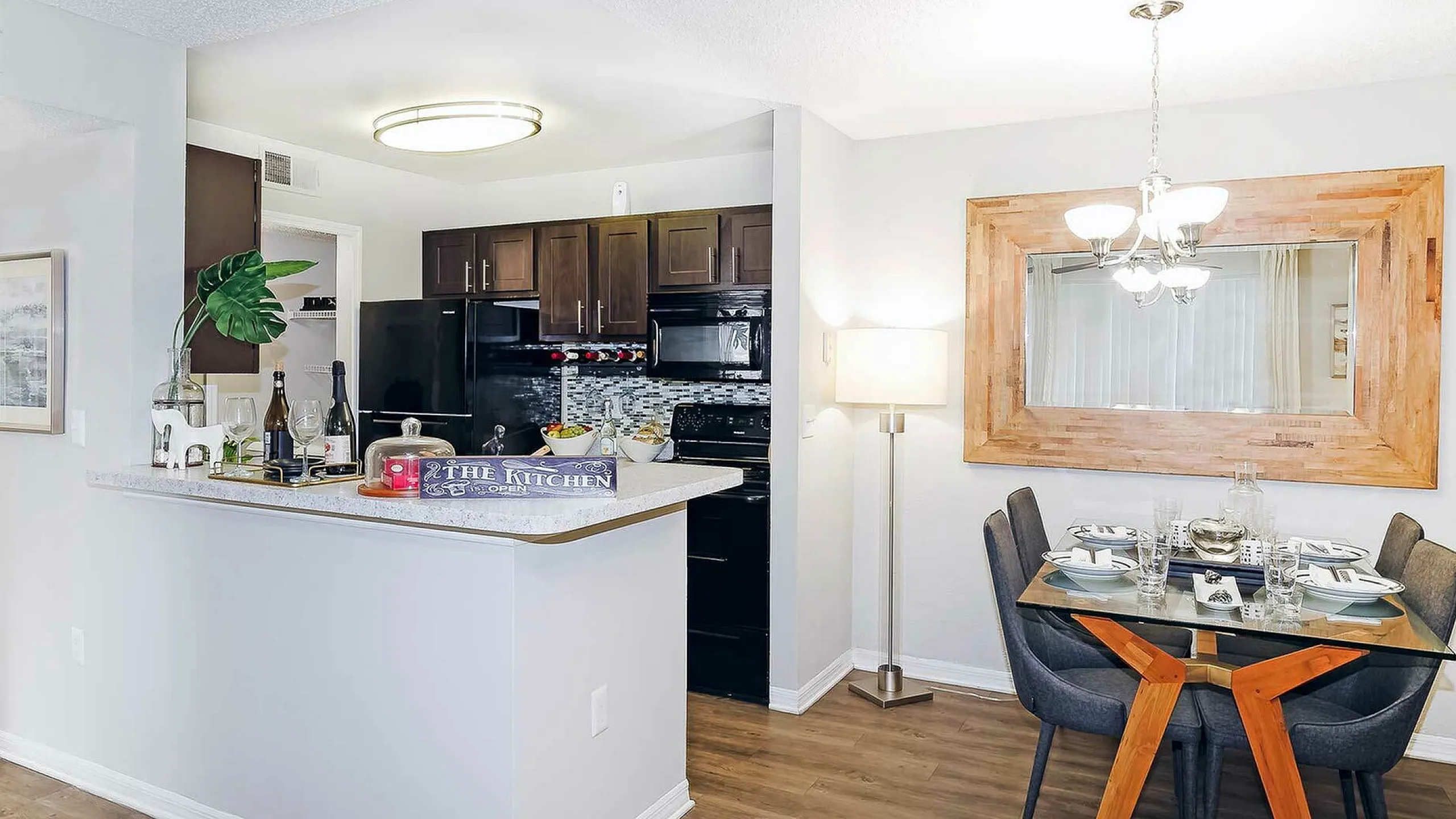 Modern kitchen and dining area with sleek appliances, elegant lighting fixture, and stylish decor.