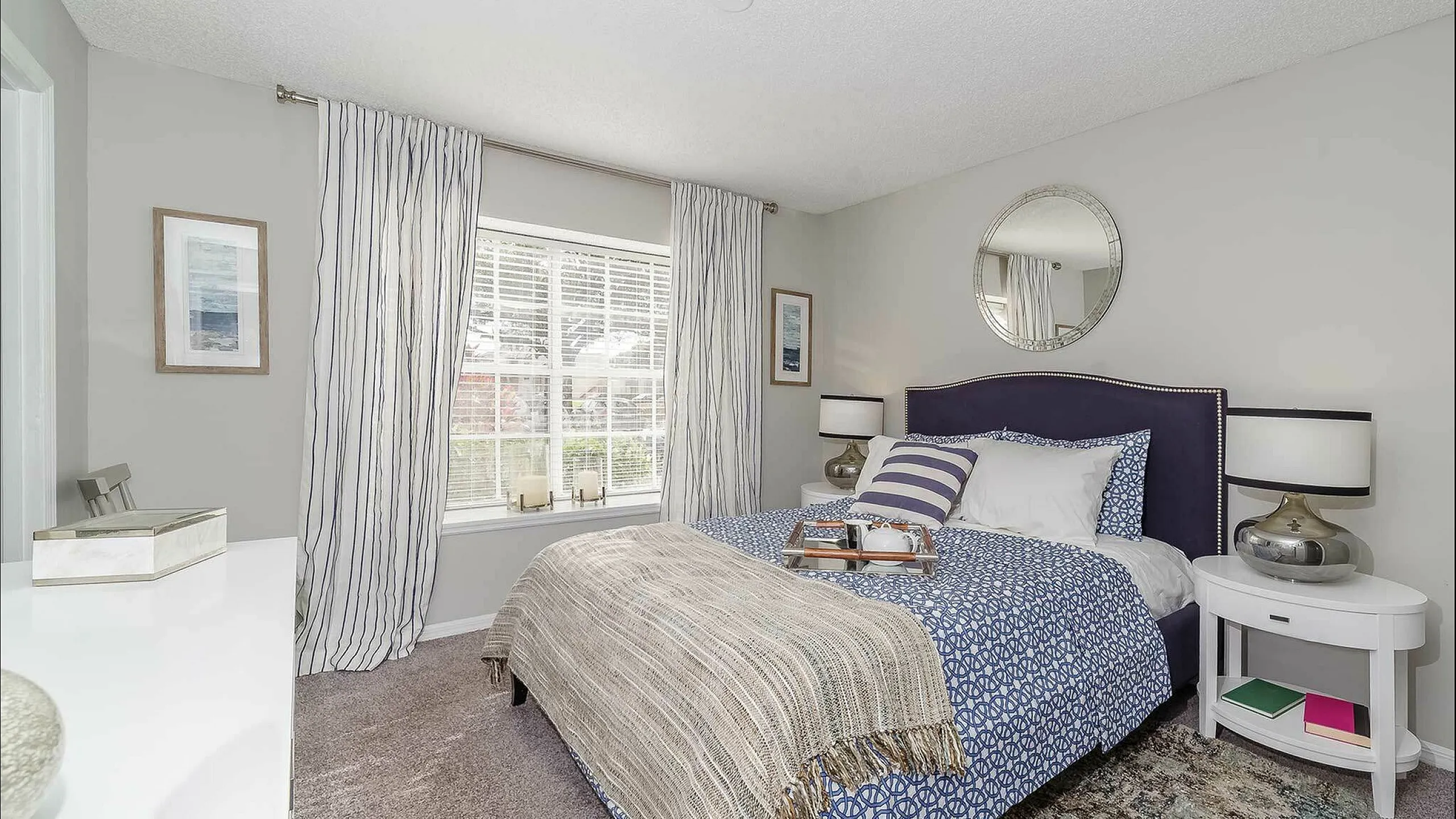 Elegant bedroom with plush bedding, stylish decor, and ample natural light streaming through large windows.