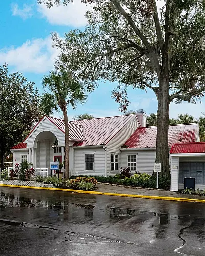 Charming community building with vibrant red roofs surrounded by lush greenery under a bright blue sky.