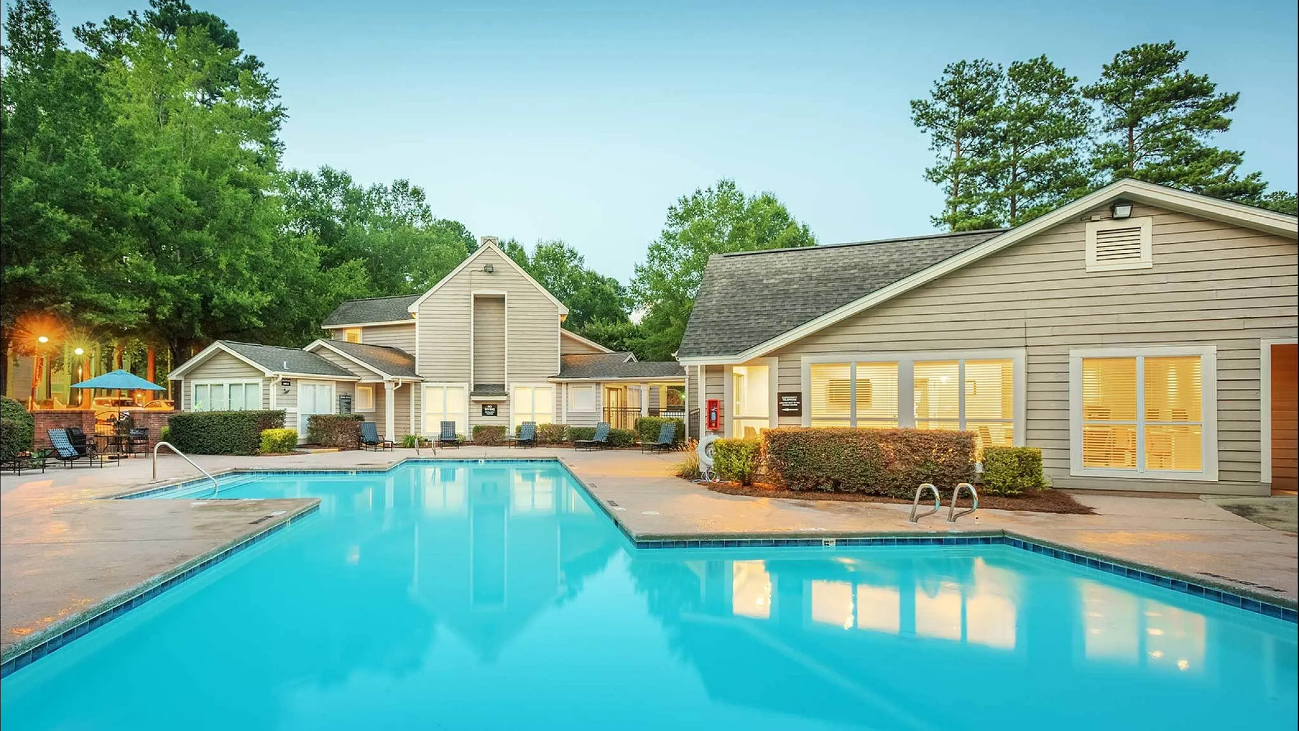 Inviting apartment complex featuring a sparkling swimming pool, cozy outdoor seating, and well-maintained landscaping for a relaxing lifestyle.