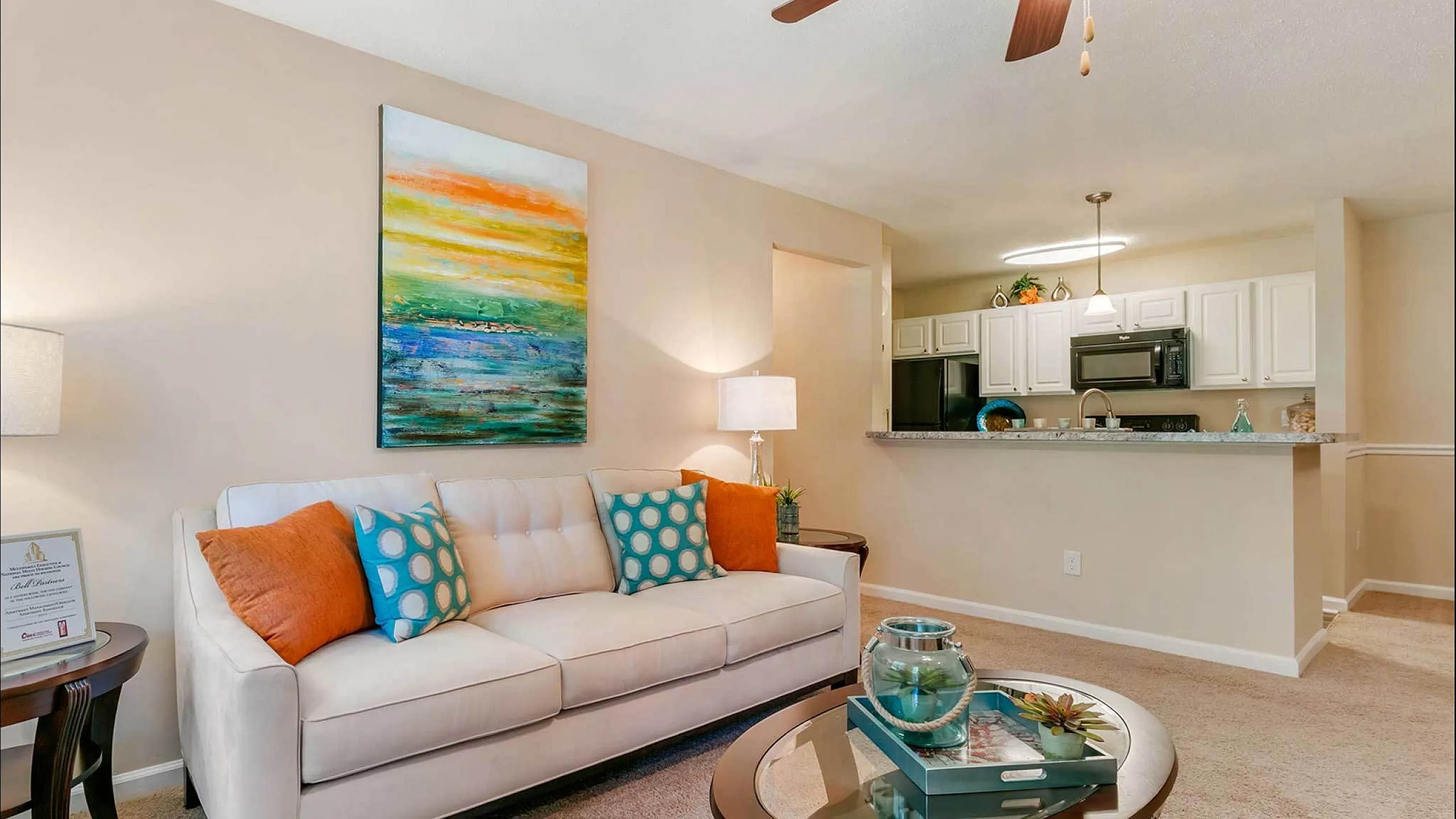 Charming living area with elegant sofa, vibrant artwork, and a cozy open kitchen, perfect for relaxing and entertaining.