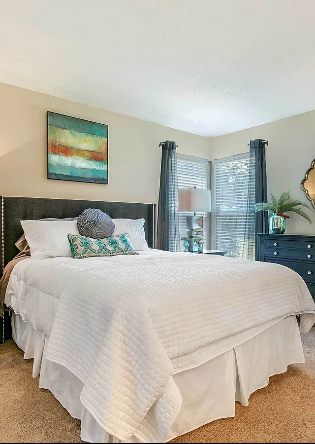 Bright and modern bedroom with a cozy bed, elegant nightstands, and a stylish dresser, offering a tranquil retreat with ample natural light.